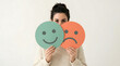© Gambar - Woman holding happy and sad faces, duality of emotions, mood swings
