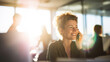 © Bonsales - Professional woman smiling, talking on phone in modern open plan office with bright sunlight and coworkers