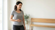 © Xenia - Smiling woman holding hand on her stomach indoors. Happy female feeling healthy digestion and wellness. Copy space for text