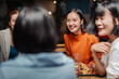 © Crystal - Asian female friends sharing a meal and drinks at an outdoor restaurant or bar, socializing and laughing during evening get together