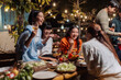 © Crystal - Happy asian friends gathering for an evening outdoor dinner party, sharing food and drinks, laughing and socializing