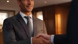 © Wuttichai - A smiling professional man shakes hands during a corporate meeting symbolizing a successful business deal and strong partnership