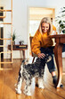 © baranq - Woman petting her schnauzer dog at home dining table