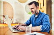 © baranq - Man working on laptop at dining table at home
