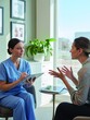 © AamirSohail - Female healthcare professional in blue scrubs listening to a patient during a medical consultation in a modern clinic office