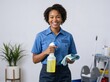© Vasiliy - Smiling African American female cleaner holding spray bottle and cloth. Professional woman in blue uniform ready for housekeeping. Janitorial service concept