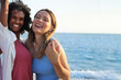 © SISMIZ - Two happy young women laughing together on a sunny beach vacation