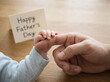 © SuperImages - Father holding small baby hand near Happy Fathers Day card