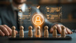 © pattozher - Human Resources Selection: A businessman's hands rest on a desk, overlooking a digital interface displaying a flowchart and glowing profile icons above a row of wooden peg figures.
