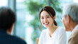 © Keopaserth - Smiling woman in white shirt with older people in bright office meeting, friendly conversation and teamwork