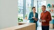 © OlgaNeuroArt - Female employee helping customer with digital tablet in modern office. Professional woman consulting mature man with brochure. Customer service and business assistance concept