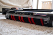 © Ina - Close-up of motorized roller brush on carpet surface. Cordless vacuum cleaner head removing dust from soft rug. Household cleaning technology concept.