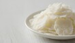 © NalLena - Natural soy wax flakes for candle making in a white ceramic bowl on light wooden background