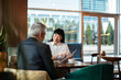 © Marko Geber - Business professionals discussing documents in modern cafe