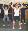 © JackF - Motivated sporty young adult man doing exercises with elastic loop band during intense workout with group in gym..