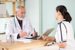 © JackF - Woman explains her complaints to an elderly male doctor sitting in front of a laptop
