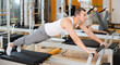 © JackF - Man in various positions performs exercises sitting and reclining on reformer. Pilates studio for maintaining physical health and strengthening muscles
