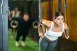 © JackF - Motivated young female athlete performing intense workout in busy urban gym setting, doing chest push-ups with gymnastic rings..