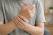 © Hossain - Person experiencing wrist pain or discomfort in a room