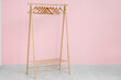 © Pixel-Shot - Wooden rack with hangers near pink wall