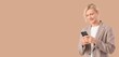 © Pixel-Shot - Young blond businessman using mobile phone on beige background with space for text
