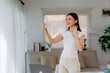 © amnaj - Young Asian woman smiling and waving during a video call on smartphone, working from her home office setup