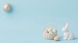 © Muktalal - Easter bunny sculpture beside basket of pastel eggs and single decorative egg on blue backdrop.