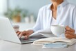 © Мария Фадеева - Business professional reading travel health advisory on laptop while holding a coffee cup for remote work background and office banner