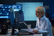 © DragonImages - Middle aged Caucasian businesswoman reviewing documents and monitoring data dashboards on computer screens in office. Ideal for business analytics, finance strategy, cybersecurity