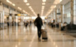 © Vhagar - A blurred view of a busy airport terminal, with travelers walking and carrying luggage. The setting conveys a sense of movement and transit.