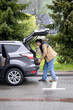 © Ina - Man placing suitcase into car trunk during mountain countryside trip. Road travel, vacation preparation, transportation and outdoor getaway lifestyle concept in nature.