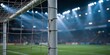© MdArshed - A close up view of a soccer goal post with netting at a stadium under bright lights
