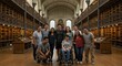 © BerkahBerkat - Grupo de pessoas posando no interior de uma biblioteca histórica com estantes de livros de madeira.