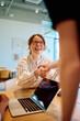 © we.bond.creations - Woman in glasses shaking hands with unseen person, celebrating a successful business deal, partnership, or collaboration in an office