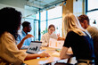 © we.bond.creations - Diverse business professionals collaborating on a project, analyzing data, and brainstorming ideas during a corporate meeting in a modern office