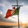 © 9parusnikov - Tattered Italian flag on a mast at sunset over the sea