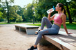 © Mediaphotos - Young woman drinking water after workout in park, resting on bench and hydrating during fitness routine. Ideal for wellness, active lifestyle, exercise recovery marketing