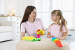 © New Africa - Spring cleaning. Happy mother and her daughter wiping dust from pouf together at home