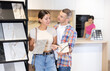 © JackF - Couple of young man and woman buyer chooses samples of ceramic tiles in hardware store