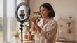 © Celso Pupo - Happy Young Female Influencer Recording Social Media Content with Smartphone and Ring Light at Home