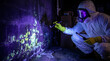 © Luluraschi - Mold inspector using UV blacklight in basement revealing toxic wall contamination