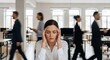 © Muhammad - Stressed businesswoman in office with blurred colleagues rushing in the background