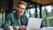 © VeretiLab - Focused middle-aged man with glasses working on a laptop outdoors at a table