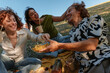 © bernardbodo - Young friends laughing and sharing snacks during picnic