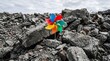 © Misbah - Vibrant multicolored plastic pinwheel toy spinning rapidly while standing firmly in the middle of a vast gray pile of jagged broken concrete rubble under a cloudy and gloomy overcast sky.