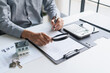 © Charlie's - Asian businessman holding magnifying glass and checking documents