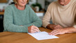 © Nova Zigres - Elderly Couple Planning Vacation and Organizing Travel Documents on Wooden Table