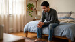 © FantasticPixel - Sad man sitting on bed in messy bedroom with natural light for mental health