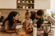 © La Famiglia - Family cooking together in kitchen, child mixing ingredients
