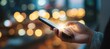 © ЮРИЙ ПОЗДНИКОВ - Hand holding smartphone with illuminated screen against blurred city lights at night